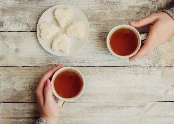 çay aşıkların eller. Ahşap arka plan üzerinde.