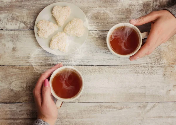 çay aşıkların eller. Ahşap arka plan üzerinde.