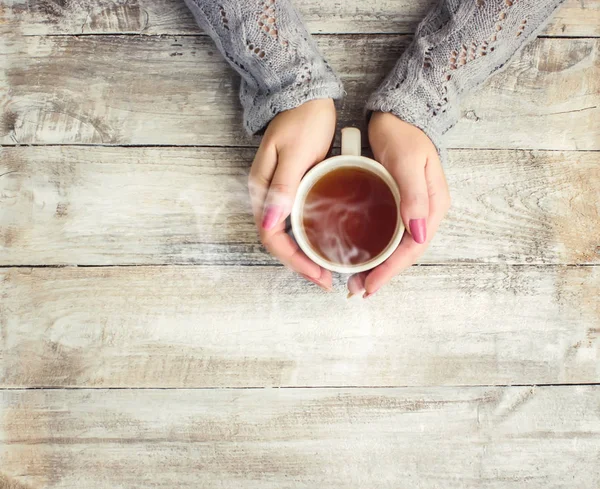 çay aşıkların eller. Ahşap arka plan üzerinde.