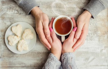 çay aşıkların eller. Ahşap arka plan üzerinde.