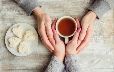 çay aşıkların eller. Ahşap arka plan üzerinde.