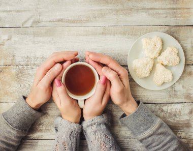 çay aşıkların eller. Ahşap arka plan üzerinde.