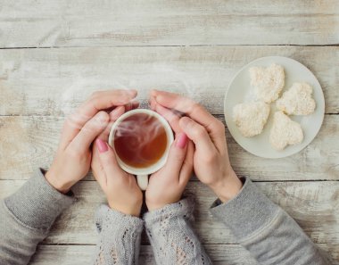 çay aşıkların eller. Ahşap arka plan üzerinde.