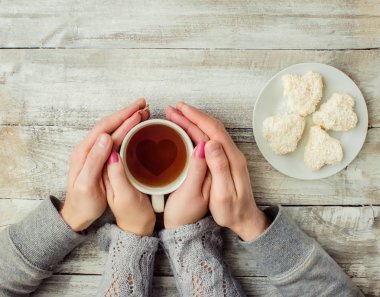 çay aşıkların eller. Ahşap arka plan üzerinde.