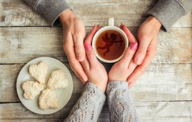 çay aşıkların eller. Ahşap arka plan üzerinde.