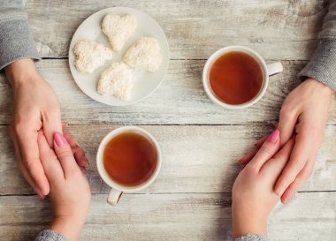 çay aşıkların eller. Ahşap arka plan üzerinde.