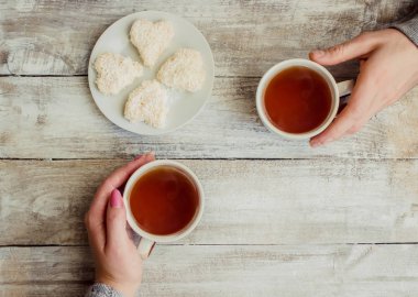 çay aşıkların eller. Ahşap arka plan üzerinde.