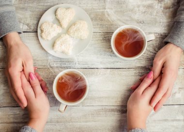 çay aşıkların eller. Ahşap arka plan üzerinde.