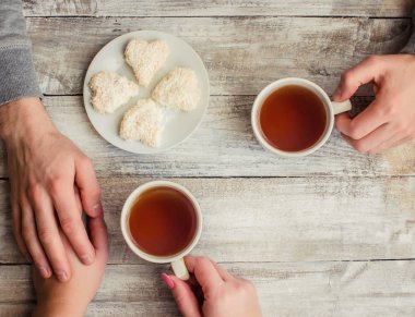 çay aşıkların eller. Ahşap arka plan üzerinde.