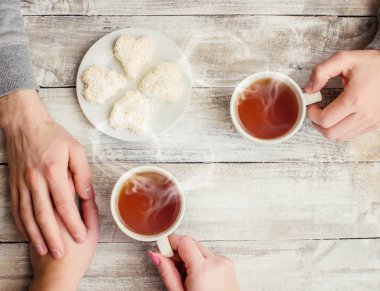 çay aşıkların eller. Ahşap arka plan üzerinde.