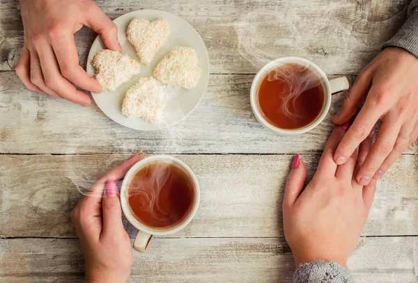 çay aşıkların eller. Ahşap arka plan üzerinde.