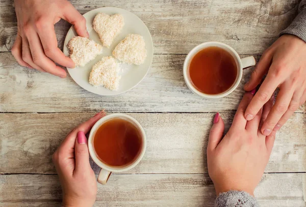 çay aşıkların eller. Ahşap arka plan üzerinde.