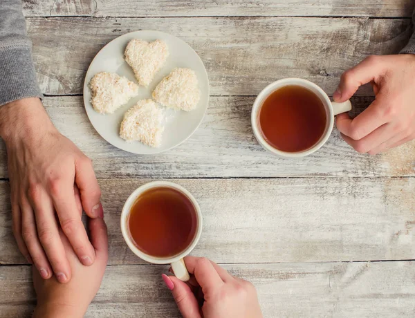 çay aşıkların eller. Ahşap arka plan üzerinde.