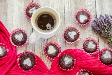 Kalpleri ve bir fincan kahve kahvaltı ile ev yapımı çikolata cupcakes. Seçici odak. Ahşap arka plan.