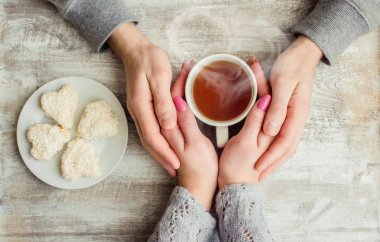 çay aşıkların eller. Ahşap arka plan üzerinde.