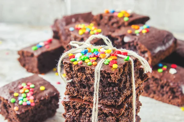 Homemade cake brownies with colored sprinkles. Selective focus. Wooden background. — Stock Photo, Image