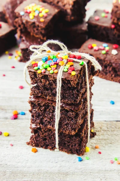 Homemade cake brownies with colored sprinkles. Selective focus. Wooden background. — Stock Photo, Image