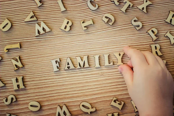 Dziecko zbiera ważne słowa z drewnianych liter. Selektywna koncentracja. — Zdjęcie stockowe