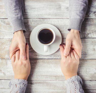 Aşıkların elinde kahvaltı için bir bardak içki. Seçici odak. 