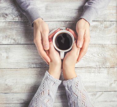 Aşıkların elinde kahvaltı için bir bardak içki. Seçici odak. 