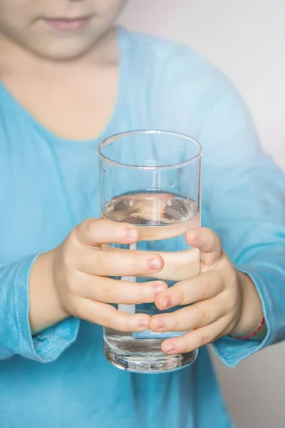 Barnet håller ett glas vatten i handen. selektivt fokus. — Stockfoto