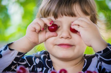 Çocuk bahçede kiraz topluyor. Seçici odak.