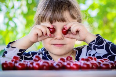 Çocuk bahçede kiraz topluyor. Seçici odak.