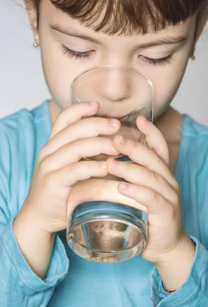 El niño sostiene un vaso de agua en sus manos. enfoque selectivo . — Foto de Stock
