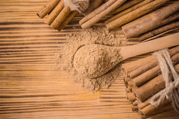 Ground cinnamon and sticks on a wooden background. selective focus. — Stock Photo, Image