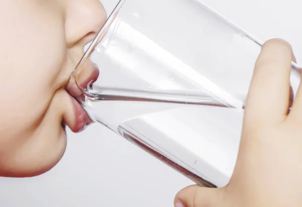 The child holds a glass of water in his hands. selective focus. — Stock Photo, Image