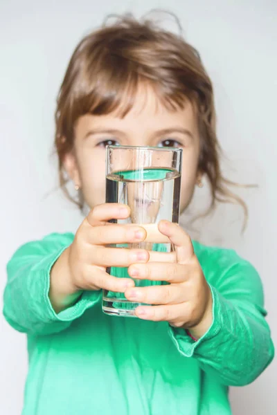 El niño sostiene un vaso de agua en sus manos. enfoque selectivo . — Foto de Stock