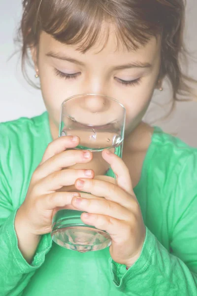 Il bambino tiene in mano un bicchiere d'acqua. focus selettivo . — Foto Stock