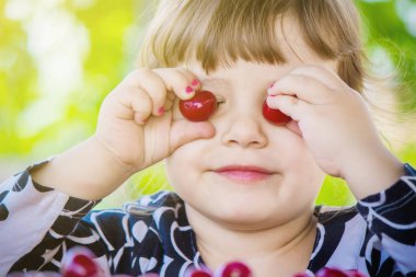 Çocuk bahçede kiraz topluyor. Seçici odak.