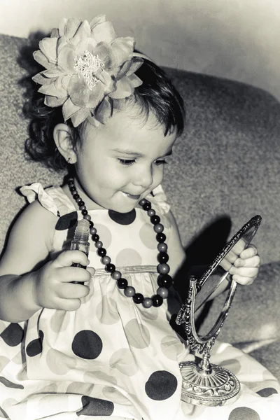 Красивая маленькая девочка смотрит в зеркало и красит губы. Селективный фокус . — стоковое фото
