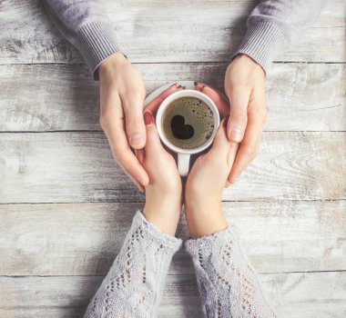 Aşıkların elinde kahvaltı için bir bardak içki. Seçici odak. 