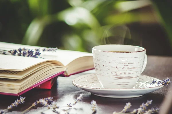 Ζεστό φλιτζάνι καφέ και διαβάζοντας ένα βιβλίο στον ελεύθερο χρόνο. Επιλεκτική εστίαση. — Φωτογραφία Αρχείου