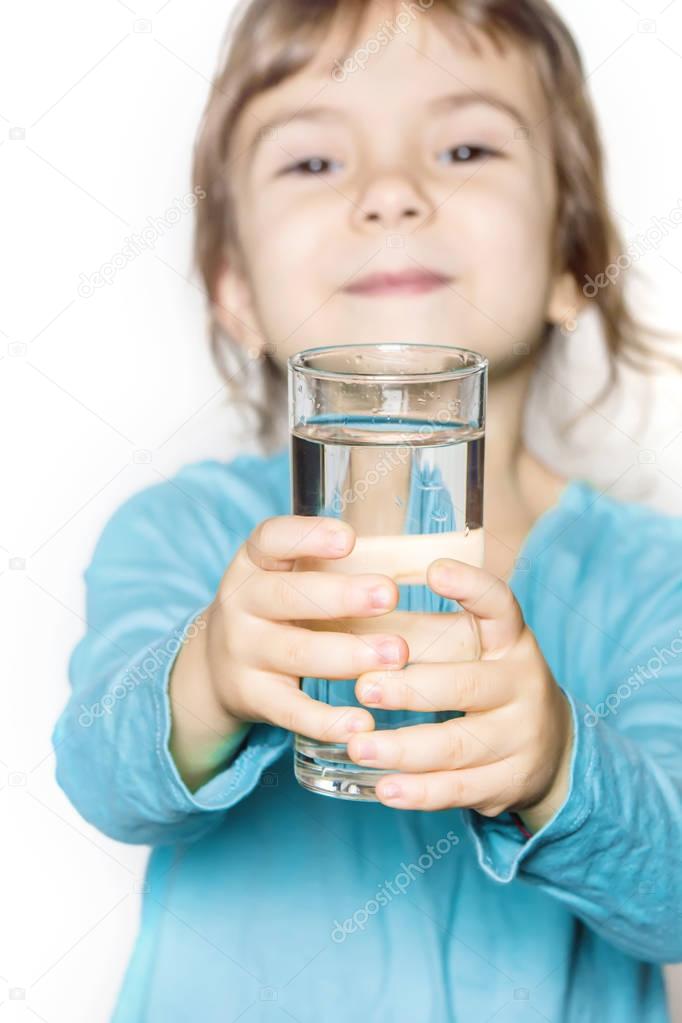 the child holds a glass of water in his hands. selective focus. 