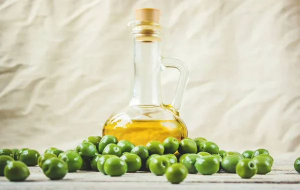 El aceite de oliva en una botella transparente sobre un fondo de madera. Enfoque selectivo . —  Fotos de Stock