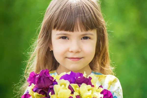 Flicka med en bukett av iris. Selektivt fokus. — Stockfoto