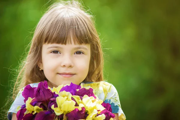 Fille avec un bouquet d'iris. Concentration sélective . — Photo