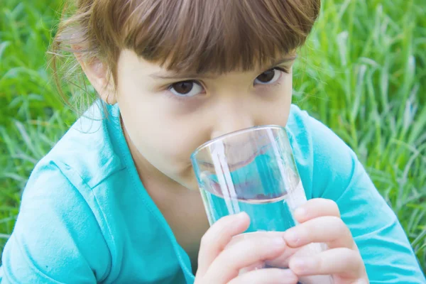 Il bambino tiene in mano un bicchiere d'acqua. focus selettivo . — Foto Stock