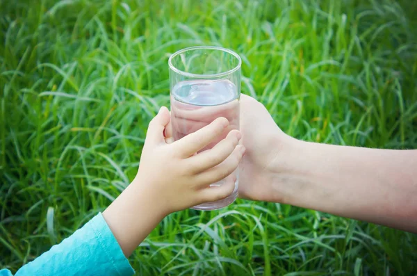 女人给孩子一杯干净的水。选择性的焦点. — 图库照片