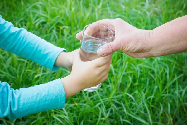 Mujer dando un vaso de agua limpia a un niño. Enfoque selectivo . — Foto de Stock