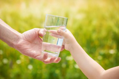 Baba çocuk bir bardak su verir. Seçici odak.