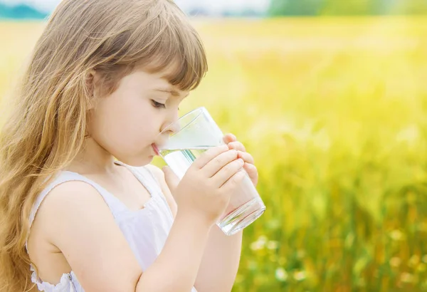 Hält das Kind ein Glas Wasser in der Hand. Selektiver Fokus. — Stockfoto