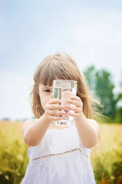 Il bambino tiene in mano un bicchiere d'acqua. focus selettivo . — Foto Stock