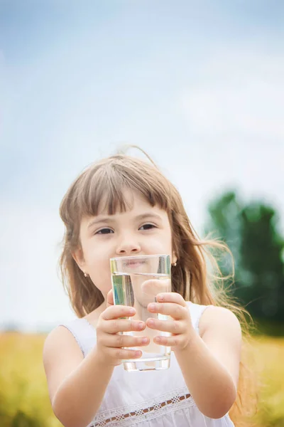 El niño sostiene un vaso de agua en sus manos. enfoque selectivo . — Foto de Stock