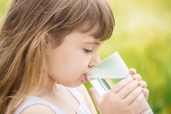 El niño sostiene un vaso de agua en sus manos. enfoque selectivo . — Foto de Stock