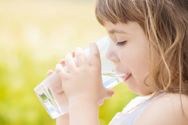 El niño sostiene un vaso de agua en sus manos. enfoque selectivo . — Foto de Stock