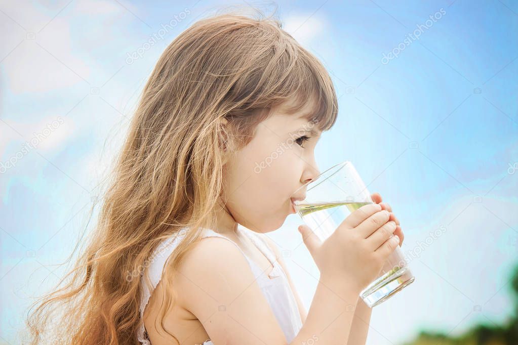 the child holds a glass of water in his hands. selective focus. 